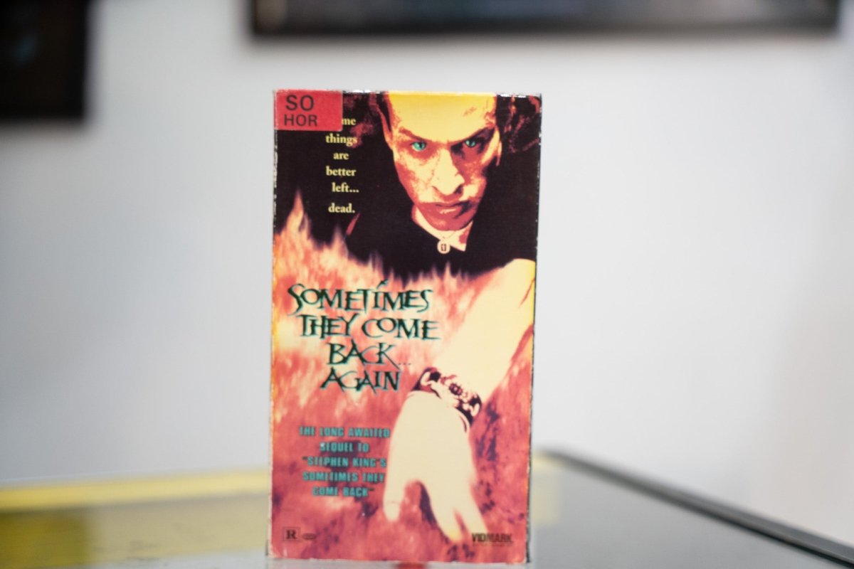 Sometimes They Come Back Again VHS fiery sleeve with dark figure glowing green eyes emerging from flames green metallic title and Vidmark Entertainment