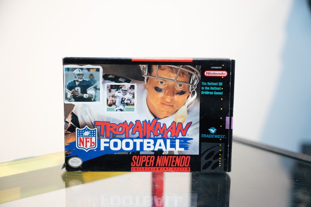 Super Nintendo Troy Aikman NFL Football box Troy Aikman Cowboys helmet close-up action photos Troy Aikman red script NFL Football text Tradewest