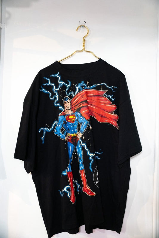 Black Superman DC Shoe Palace tee with full-body classic Superman illustration in blue suit and red cape with lightning bolts on black background