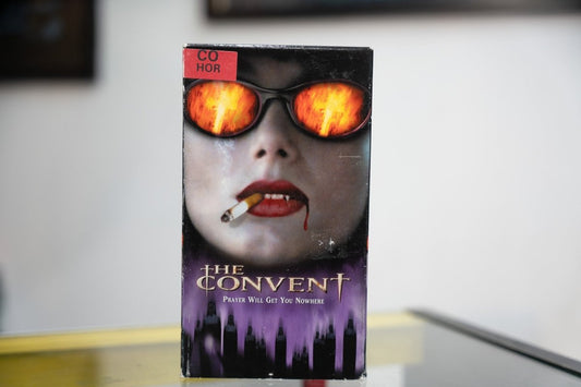 The Convent VHS dark sleeve with woman in fire-reflecting sunglasses vampire fangs cigarette gold THE CONVENT title with cross and Prayer Will Get You Nowhere tagline