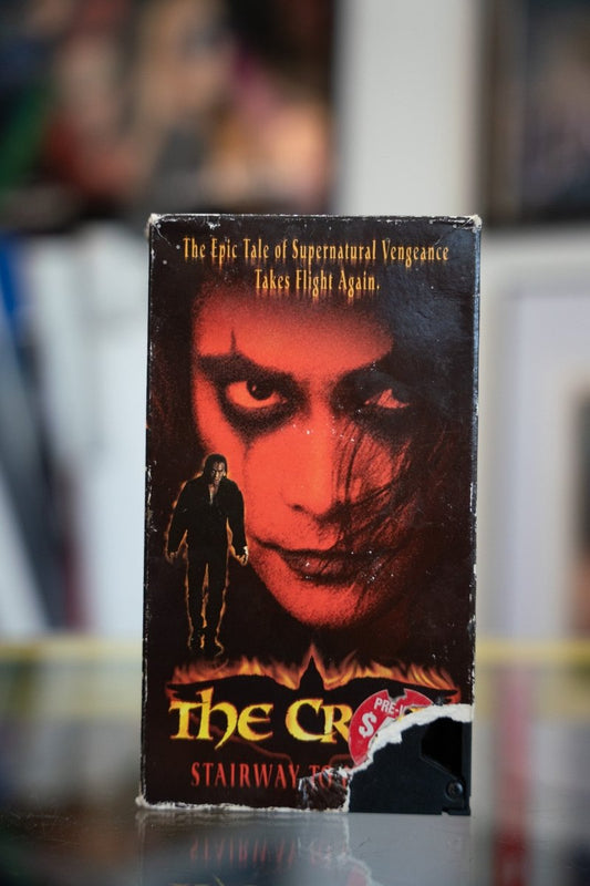 The Crow Stairway to Heaven VHS tape with dark red-lit face in crow makeup and silhouette walking through flames with gold Gothic title