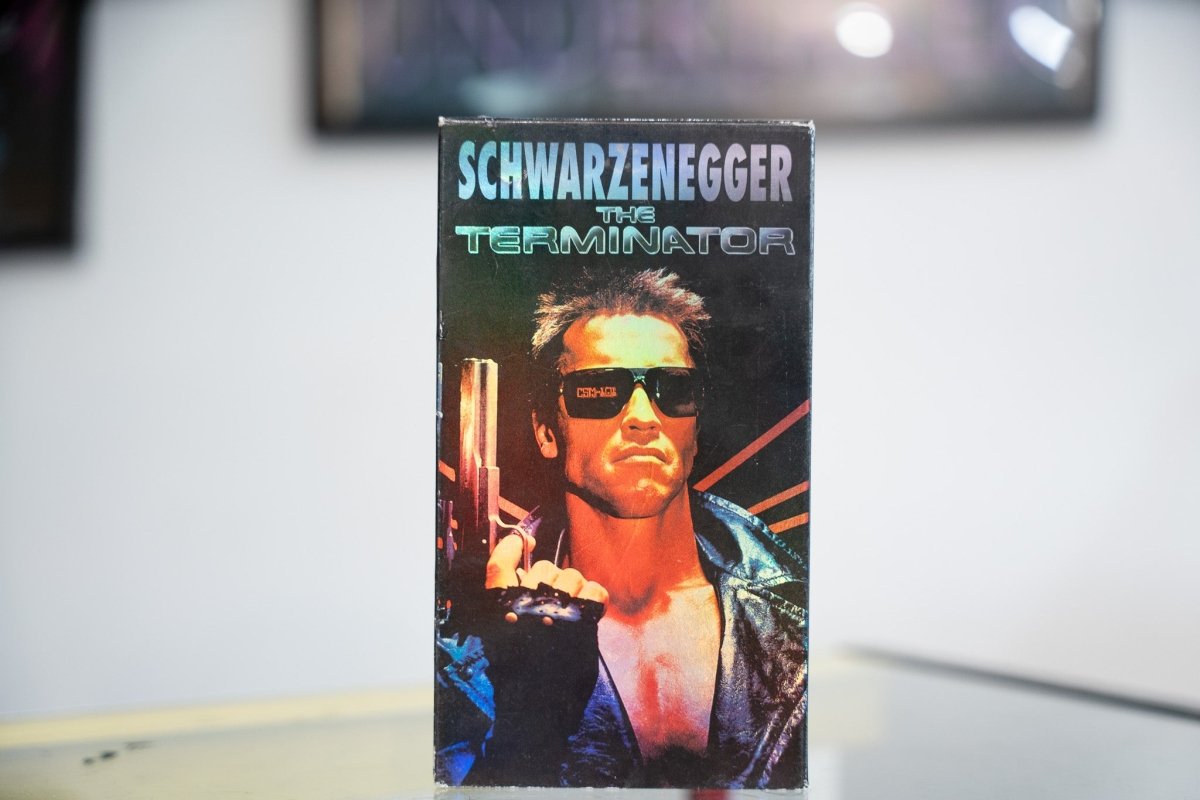 The Terminator VHS dark holographic sleeve with Schwarzenegger in leather jacket sunglasses gun red orange lighting metallic silver title CBS FOX
