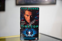 Timecop VHS dark blue sleeve with Van Damme close-up holding gun clock faces time vortex glowing portal teal TIMECOP title MCA Universal