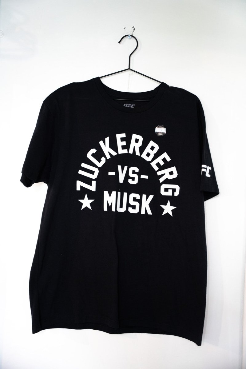 Black UFC Zuckerberg vs Musk t-shirt with white arched ZUCKERBERG text VS and MUSK lettering with stars UFC sleeve logo size XL