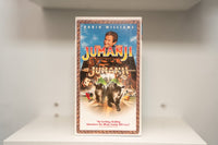 VHS Jumanji Robin Williams peeking over board game rhinoceros stampede blue sky tropical foliage JUMANJI gold green text TriStar
