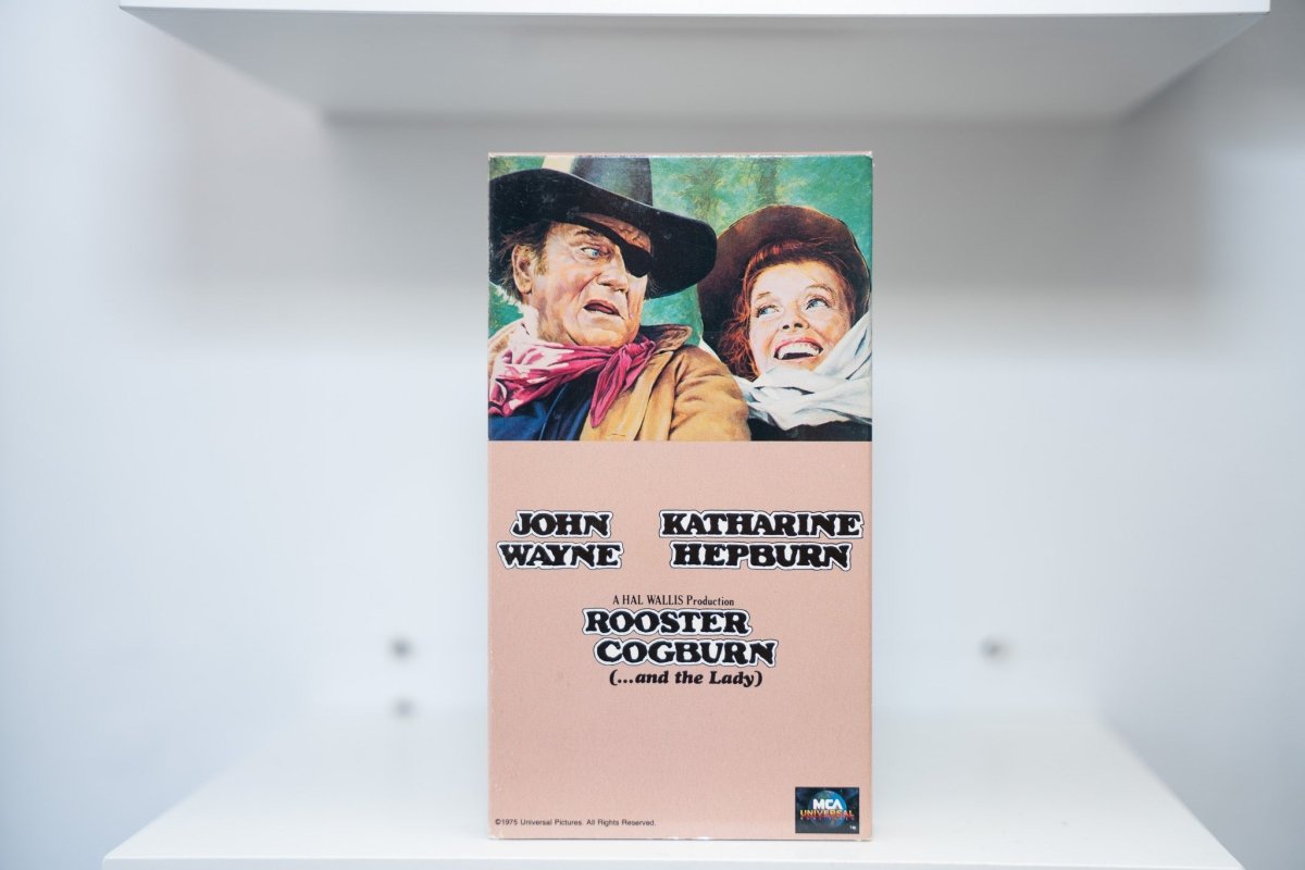 VHS Rooster Cogburn painted cover John Wayne black cowboy hat Katharine Hepburn bonnet ROOSTER COGBURN black text and the Lady MCA Universal
