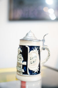 Collectible vintage German mini beer stein with Froh Gemut text and decorative glazed ceramic body in cream and blue tones