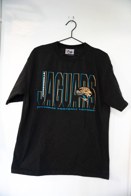 Black vintage Majestic Jacksonville Jaguars shirt with teal JACKSONVILLE text, outlined JAGUARS lettering, and snarling jaguar head logo