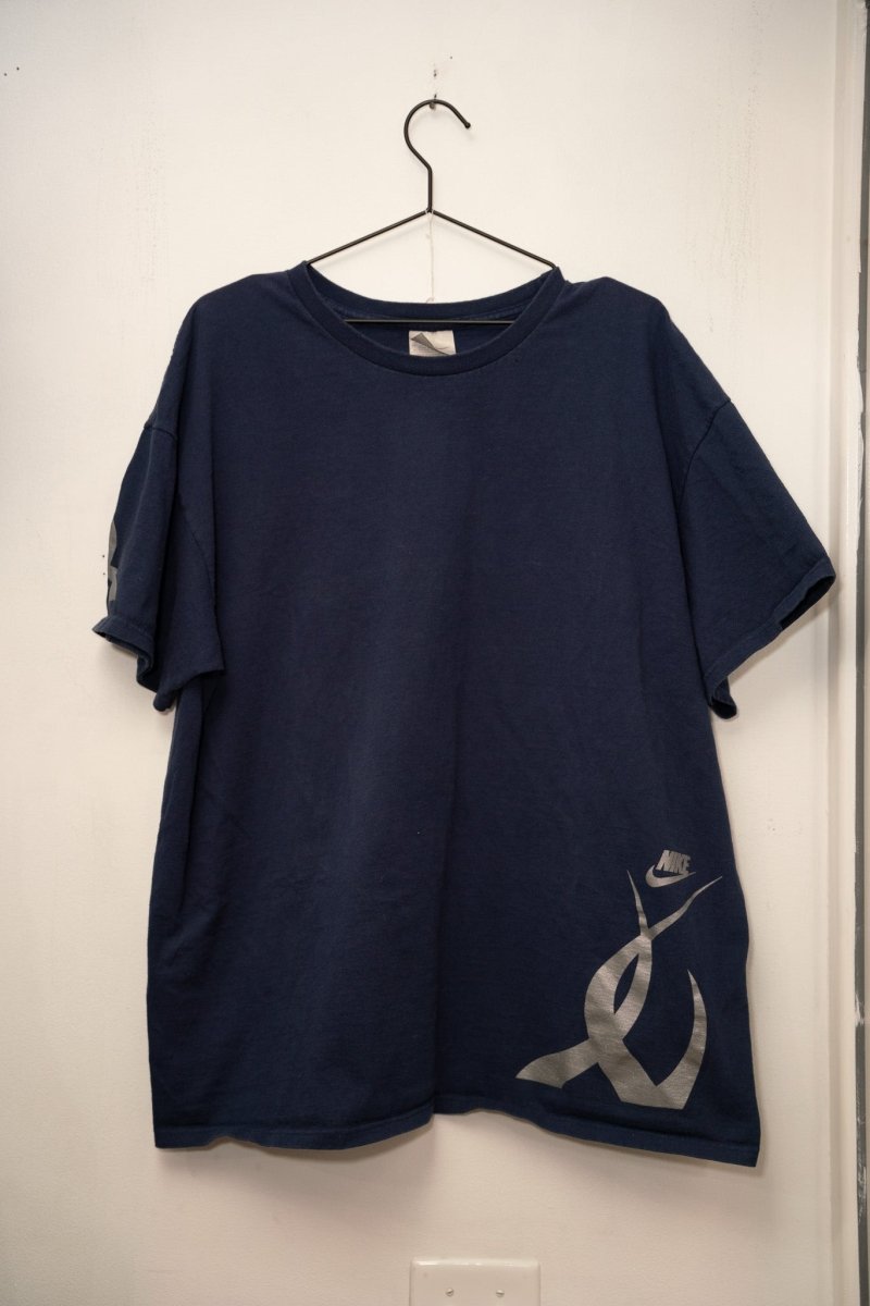 Navy blue vintage Nike Swoosh tee silver gray Nike wordmark logo lower right oversized abstract swoosh graphic sleeve detail