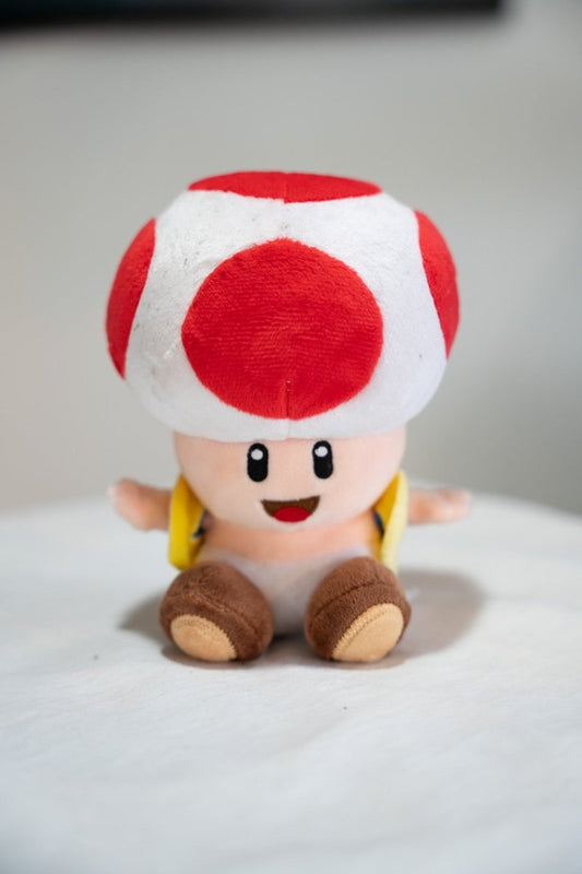 Vintage Toad Super Mario Bros plush toy with white red spotted mushroom cap cheerful face yellow vest brown shoes sitting pose
