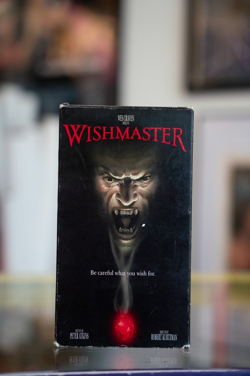 Wishmaster VHS tape with demonic Djinn face with green eyes emerging from darkness above glowing red jewel with red Gothic title