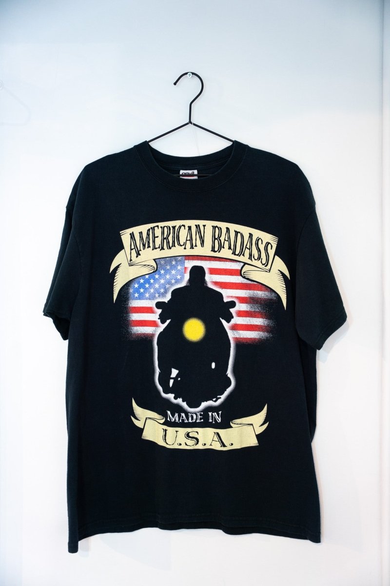 Black WWF Undertaker American Badass tee AMERICAN BADASS banner American flag motorcycle rider silhouette glowing headlight MADE IN USA banner
