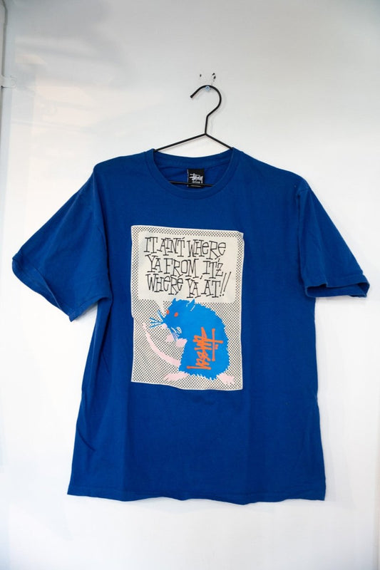 Royal blue Y2K Stussy rat shirt with black and white comic-style cartoon rat graphic and IT AIN'T WHERE YA FROM IT'Z WHERE YA AT text